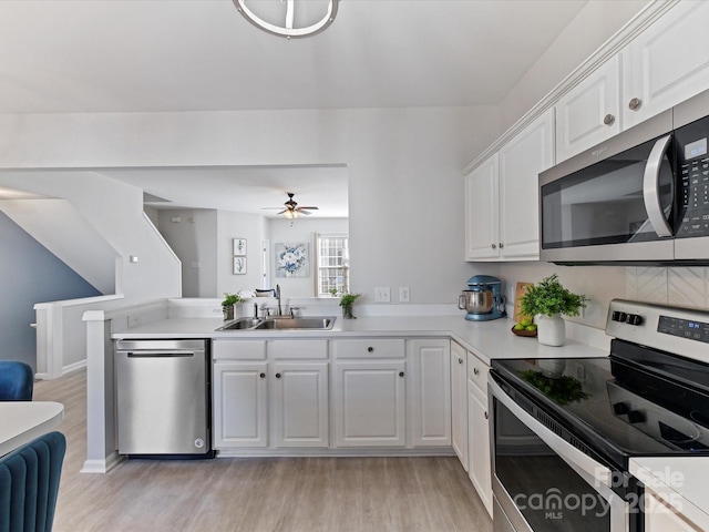 kitchen with a sink, white cabinetry, light wood-style floors, light countertops, and appliances with stainless steel finishes