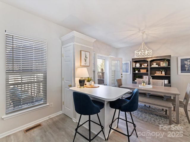 dining space featuring wood finished floors, visible vents, and baseboards