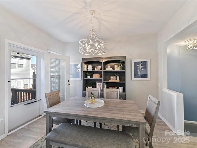 dining area with a chandelier, light wood-style flooring, and baseboards