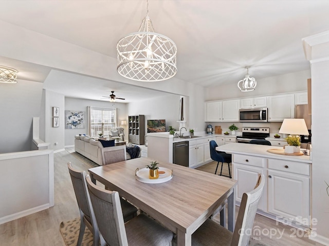 dining space featuring a ceiling fan, light wood-type flooring, and baseboards