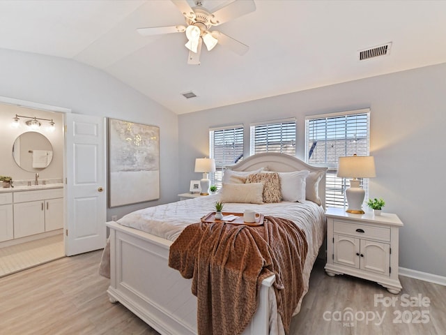 bedroom featuring lofted ceiling, a sink, visible vents, and light wood-style floors