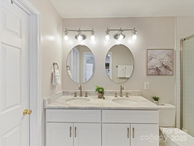 bathroom featuring a tile shower, double vanity, a sink, and toilet