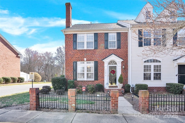 view of front of property with a fenced front yard, brick siding, and a chimney