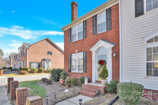 view of front of home featuring brick siding and a chimney