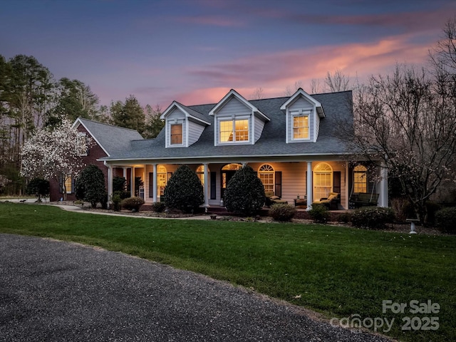 new england style home featuring covered porch and a front yard