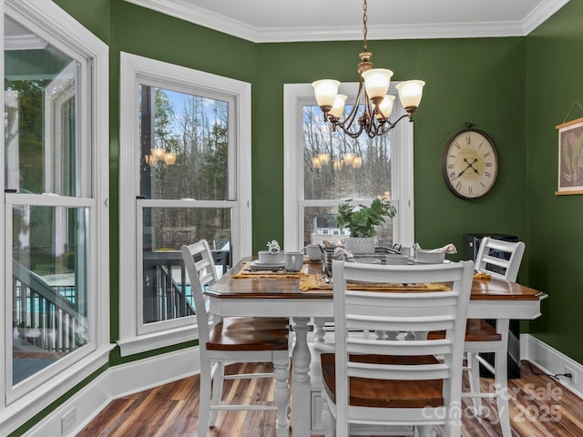 dining area featuring baseboards, ornamental molding, wood finished floors, and an inviting chandelier