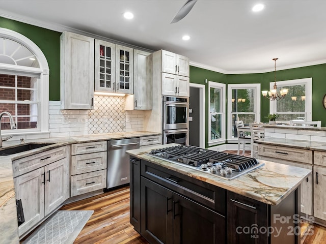 kitchen featuring light wood-style floors, crown molding, stainless steel appliances, and a sink