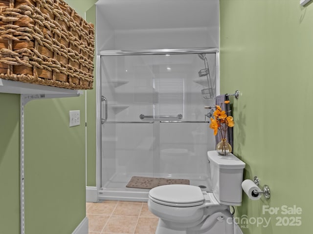 full bath featuring baseboards, a shower stall, toilet, and tile patterned floors