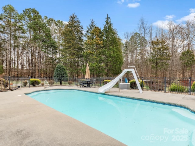 view of swimming pool with a fenced in pool, fence, and a water slide