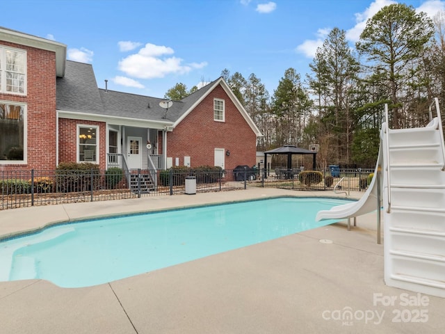 view of swimming pool featuring a fenced in pool, a water slide, fence, and a gazebo