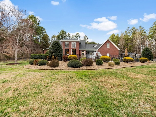 view of front facade featuring a front yard, brick siding, and fence