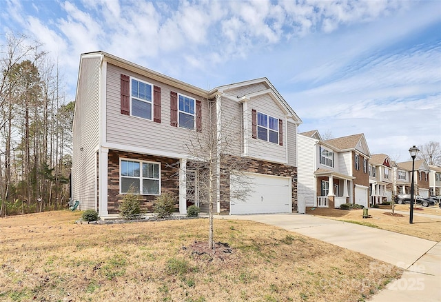 view of property featuring a garage, a residential view, concrete driveway, and a front yard