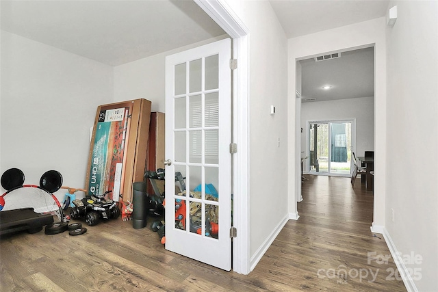 corridor featuring wood finished floors, visible vents, and baseboards