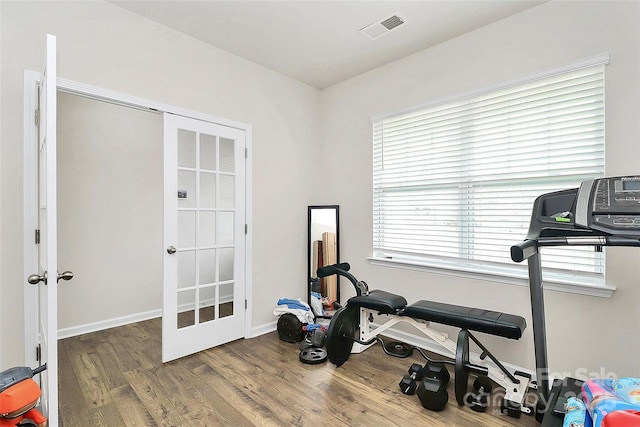 exercise room featuring french doors, visible vents, baseboards, and wood finished floors