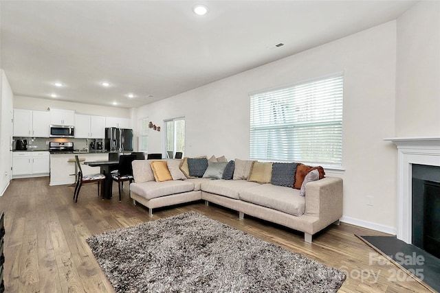 living room with a fireplace, baseboards, wood finished floors, and recessed lighting