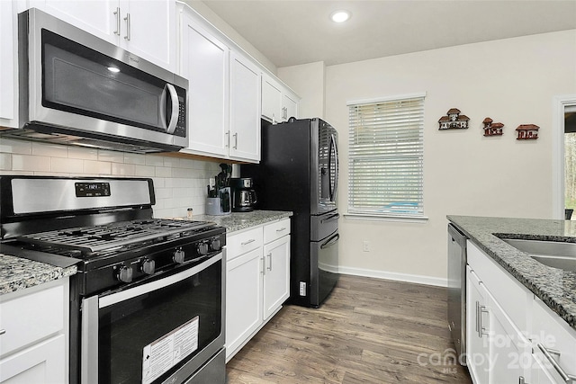 kitchen with dark wood-type flooring, white cabinetry, stainless steel appliances, and backsplash