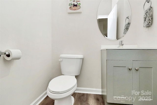 bathroom featuring toilet, vanity, baseboards, and wood finished floors