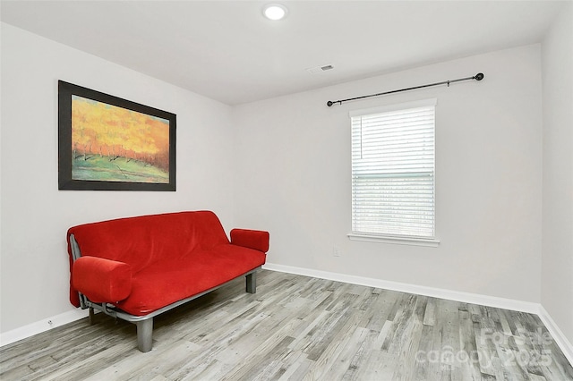 living area featuring visible vents, baseboards, and wood finished floors