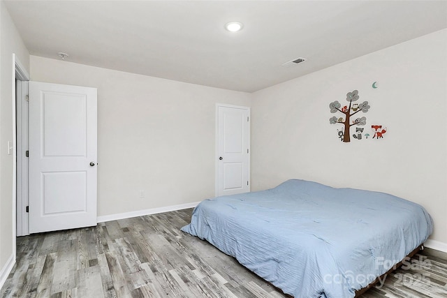 bedroom with visible vents, baseboards, and wood finished floors