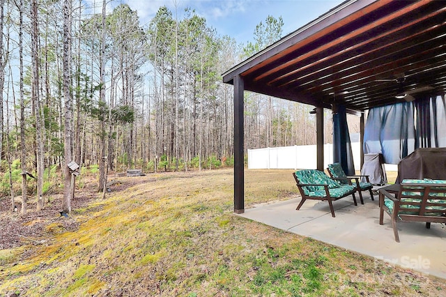 view of yard featuring a forest view, a patio area, and fence