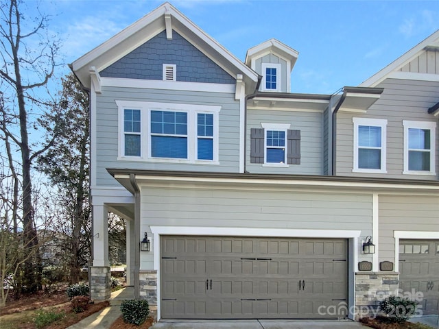 view of front of home featuring an attached garage, stone siding, and concrete driveway