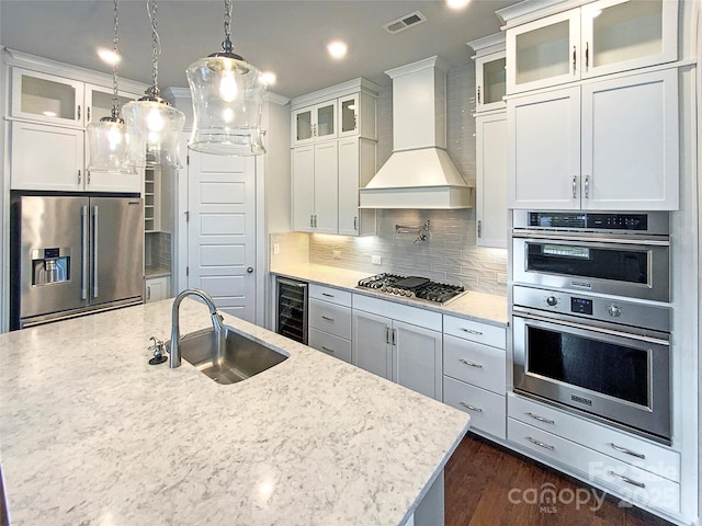 kitchen with beverage cooler, visible vents, custom range hood, stainless steel appliances, and a sink