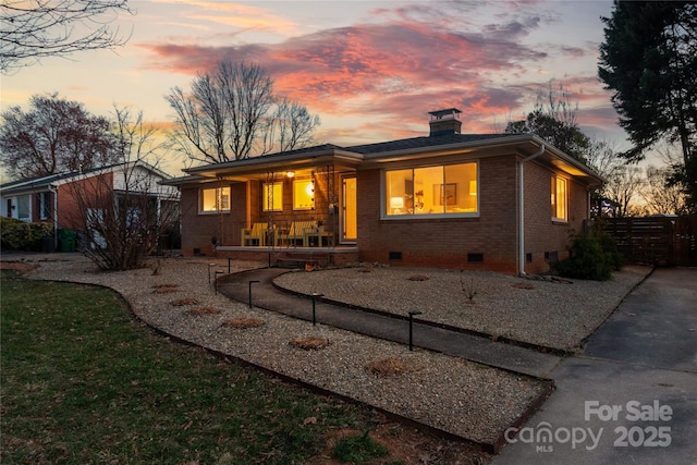 view of front facade featuring a porch, brick siding, fence, crawl space, and a chimney