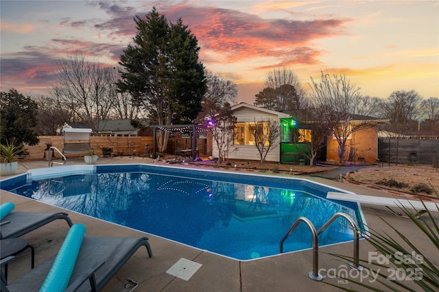 view of pool with a fenced in pool, a patio area, fence, and a diving board