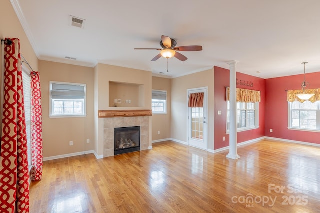 unfurnished living room featuring a tile fireplace, wood finished floors, and ornate columns