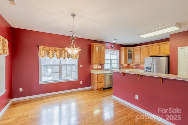 kitchen featuring visible vents, light wood-style flooring, a breakfast bar, stainless steel appliances, and light countertops