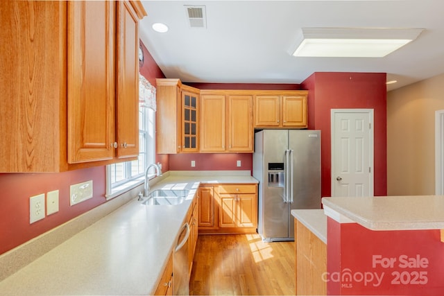 kitchen with light countertops, visible vents, appliances with stainless steel finishes, light wood-style floors, and a sink