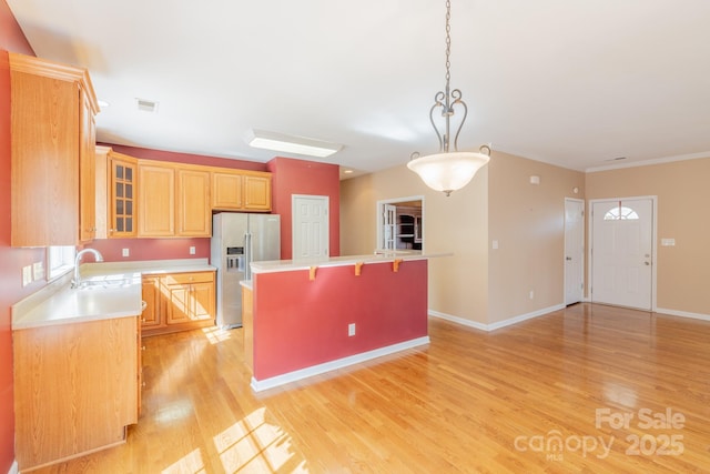 kitchen featuring a center island, a breakfast bar area, visible vents, a sink, and stainless steel fridge