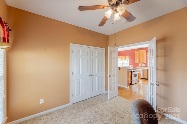 unfurnished bedroom with baseboards, a ceiling fan, light colored carpet, french doors, and a closet