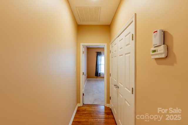 corridor with baseboards, visible vents, and dark wood-type flooring