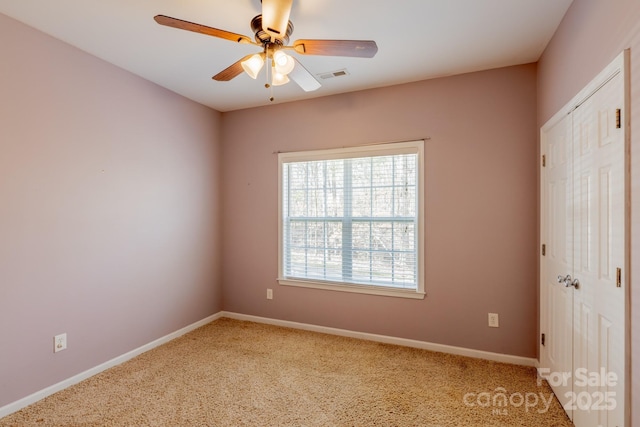 unfurnished room with baseboards, carpet flooring, visible vents, and a ceiling fan