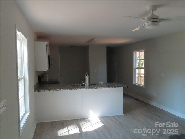 635 Acre Ct, York, SC 29745 - kitchen with a peninsula, light stone countertops, white cabinetry, a sink, and light wood-style flooring