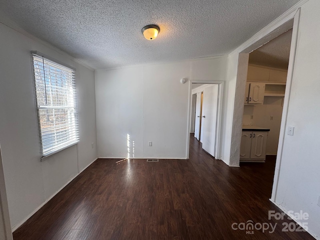 unfurnished room featuring dark wood-style floors, a textured ceiling, and visible vents