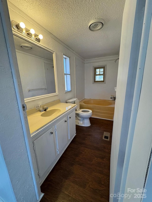 full bathroom featuring visible vents, toilet, a textured ceiling, vanity, and wood finished floors