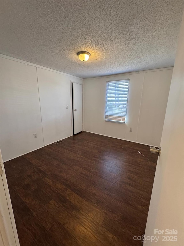 spare room featuring a textured ceiling and wood finished floors