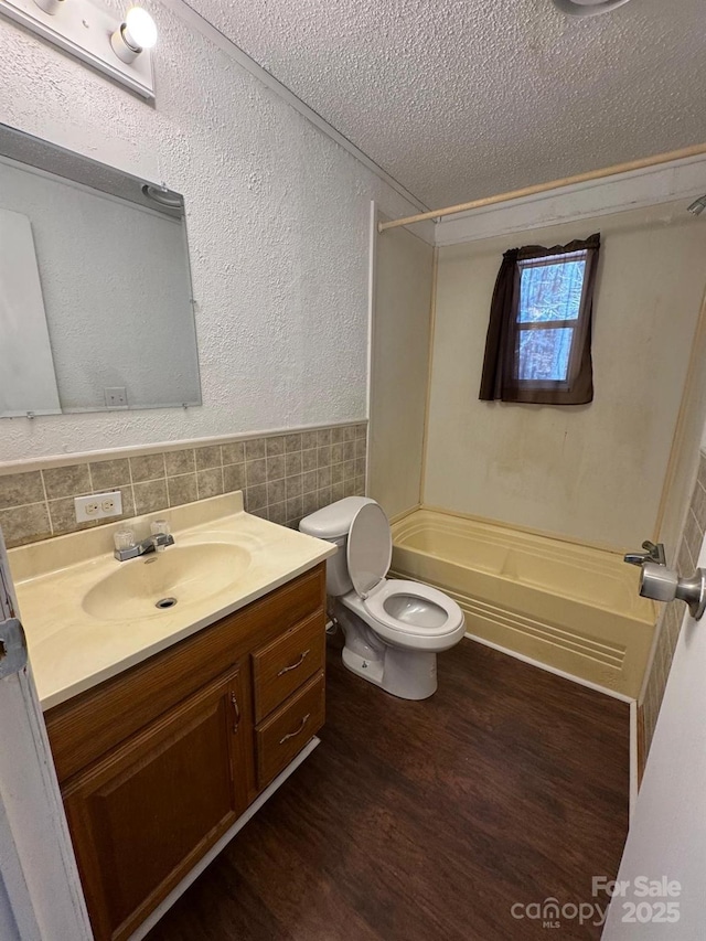 full bath featuring toilet, wainscoting, a textured ceiling, vanity, and wood finished floors