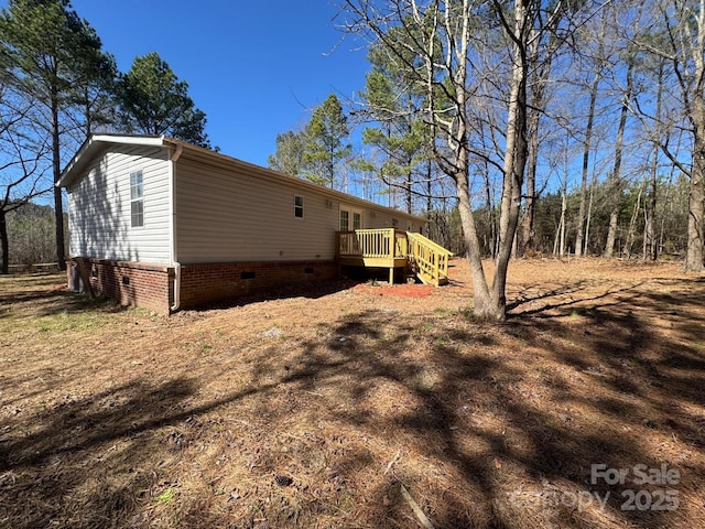 view of side of property with crawl space and a deck