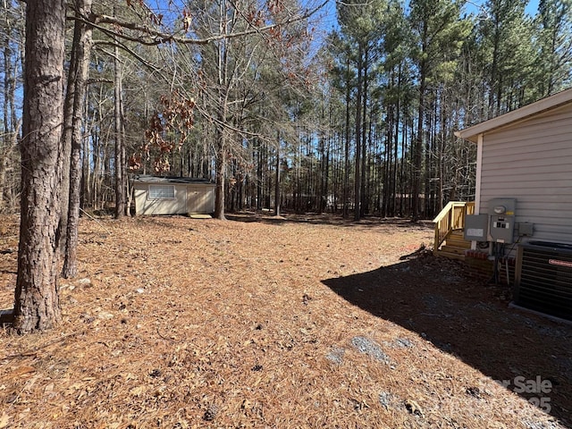 view of yard featuring a shed, central AC unit, and an outdoor structure