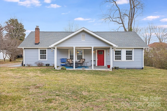 view of front of property with a shingled roof, a chimney, and a front lawn