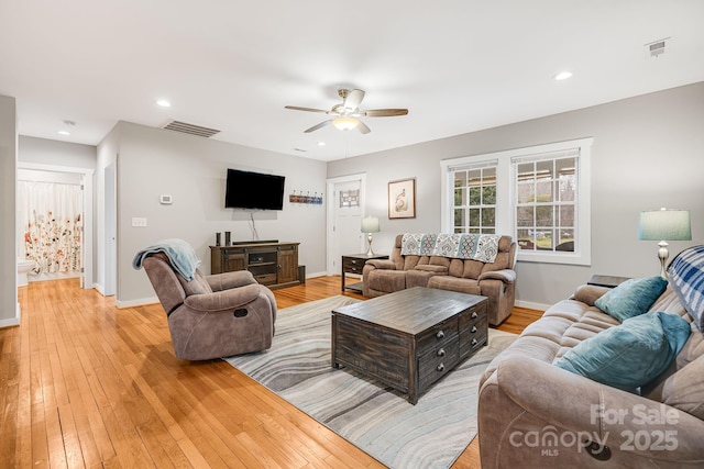 living room featuring visible vents, light wood-style flooring, and baseboards