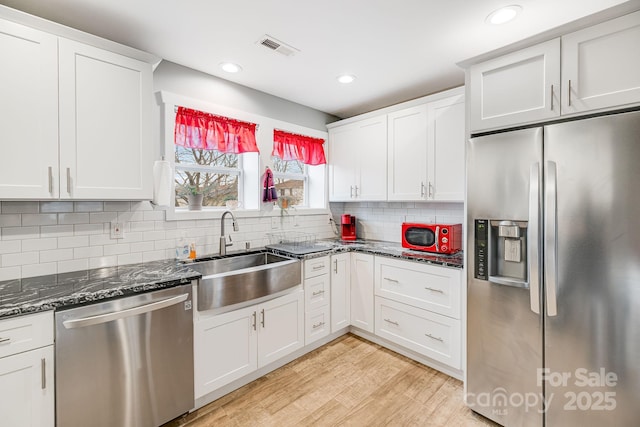 kitchen featuring light wood finished floors, visible vents, stainless steel appliances, white cabinetry, and a sink