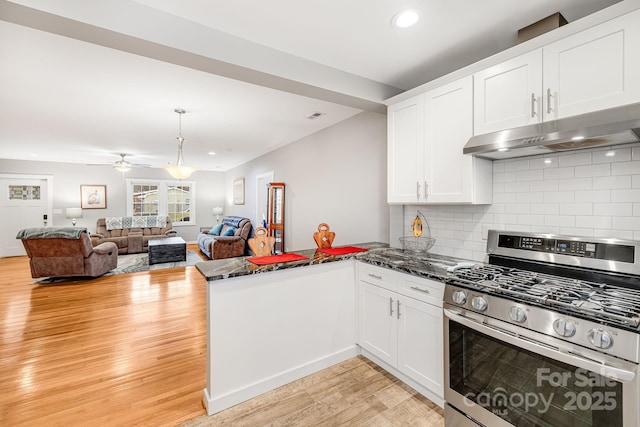 kitchen with light wood finished floors, gas stove, white cabinets, a peninsula, and under cabinet range hood