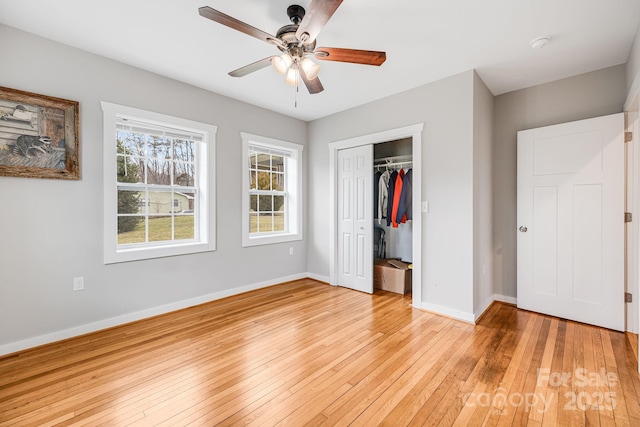 unfurnished bedroom featuring light wood-type flooring, a ceiling fan, baseboards, and a closet