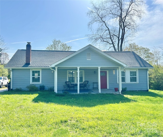 view of front of home featuring roof with shingles, a chimney, and a front lawn