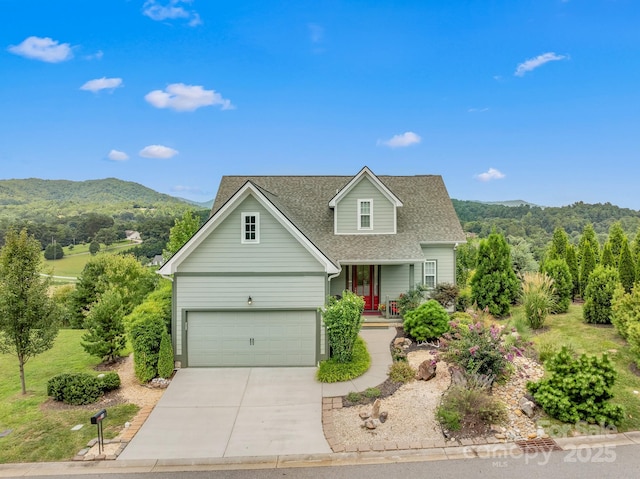 view of front of home featuring a shingled roof, concrete driveway, and a mountain view