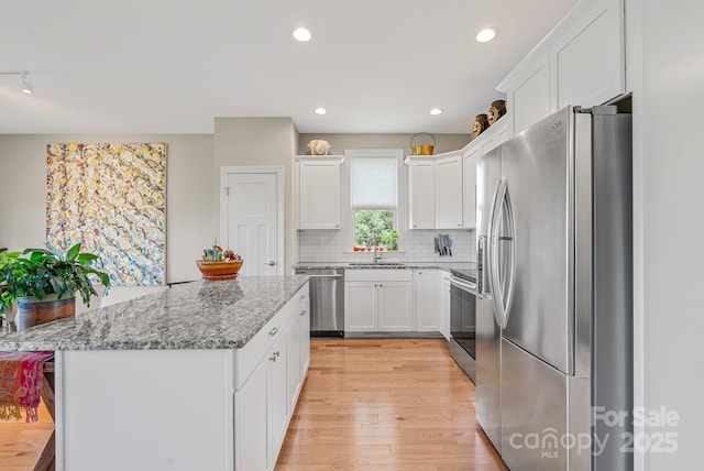 50 Rose Creek Rd, Leicester, NC 28748 - kitchen with decorative backsplash, a kitchen island, white cabinets, a sink, and appliances with stainless steel finishes